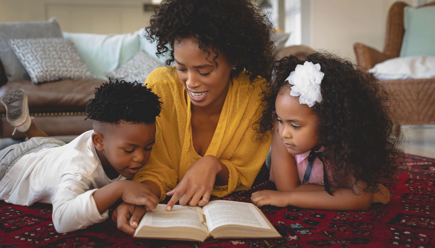 Mother reading a book to her son and daughter